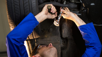 mecanico revisando la suspension del vehiculo en un foso