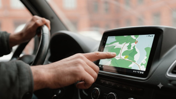 Conductor interactuando con el mapa de navegación GPS en la pantalla táctil integrada en el salpicadero del coche